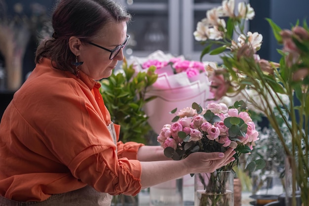 Flower shop assistants florist with laptop working checking orders lot of flowers around interior