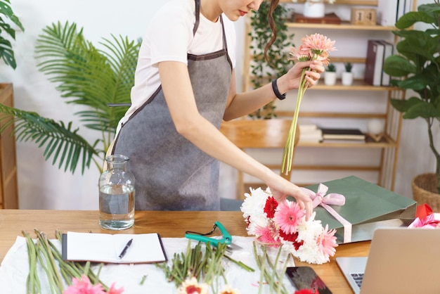 Flower shop concept Female florist grab colorful gerbera in shopping bag to arranging in vase