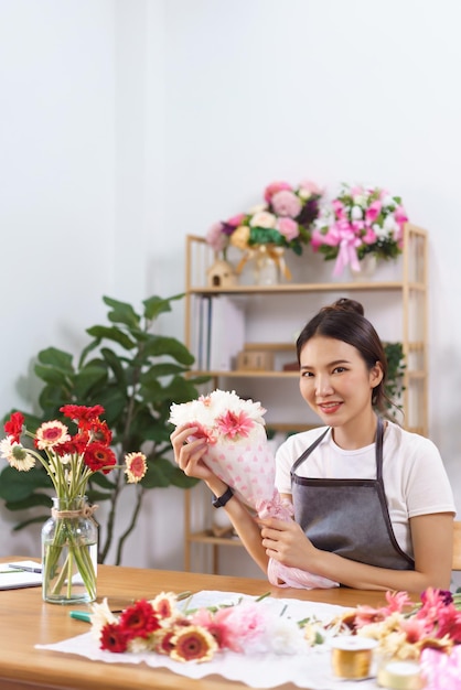 Flower shop concept Female florist smile and holds colorful flower bouquet with paper and ribbon