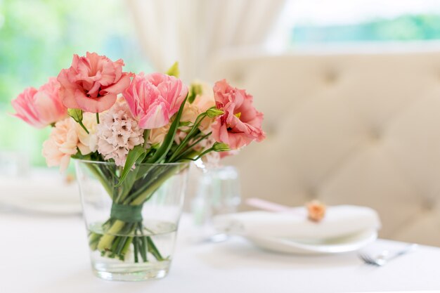 Flower table decorations for holidays and wedding dinner. Table set for holiday wedding reception in outdoor restaurant.