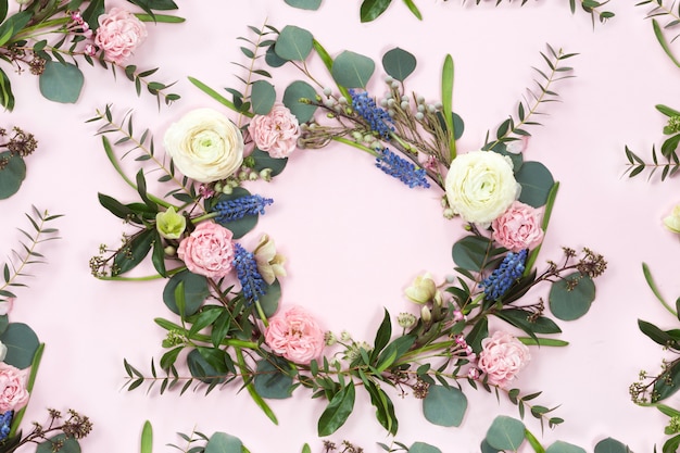 Flower wreath frame with fresh branches of pion-shaped roses and eucalyptus leaves isolated on white background, flat lay and top view