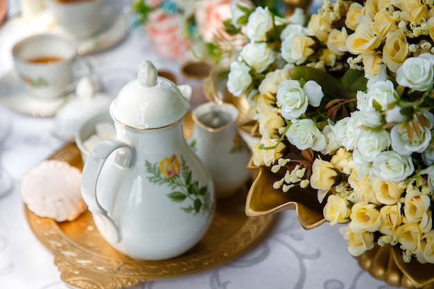 Flowers, ceramic teapot, marshmallows on a tray on the table