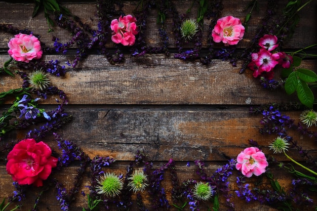 Flowers in a circle on a wooden background Postcard for the holiday Roses geraniums lavender sage and hairy chestnuts are placed along the edges on dark boards Background copy space flat lay