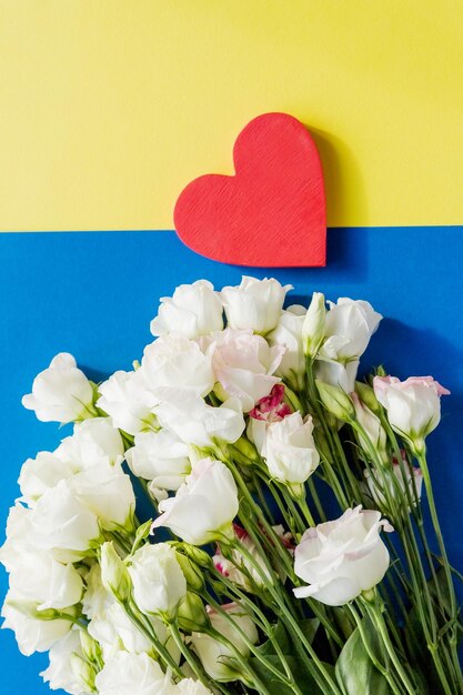 Flowers composition an red hearteustoma flowers on blue yellow background Flat lay top viewCopy space Valentine's Day wedding composition