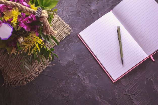 Flowers on a dark background next to a notebook