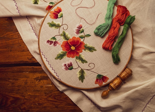 Photo flowers embroidery on white textile in hoop wooden background traditional ukrainian floss stitch emb