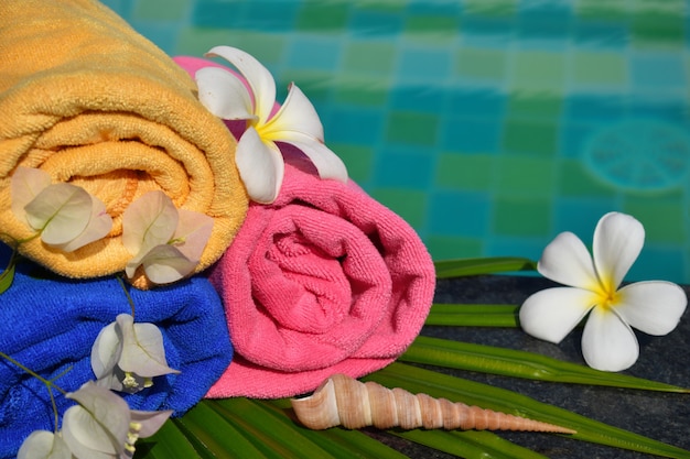 Flowers, towel and water. Recreation at the pool. Tropical beauty spa. Relax and enjoy in the tropics.