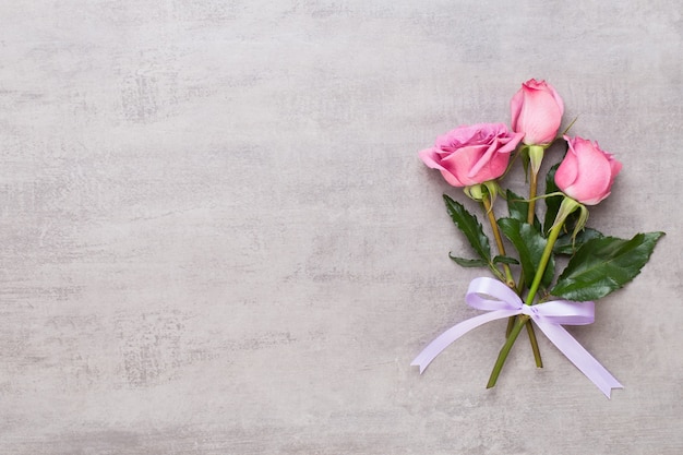 Flowers valentine day composition. Frame made of pink rose on gray. Flat lay, top view, copy space.