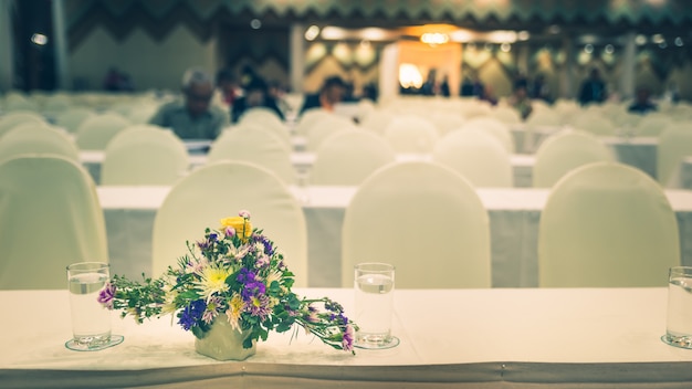 Flowers in vase with blurred meeting room, Convention hall defocus abstract and background