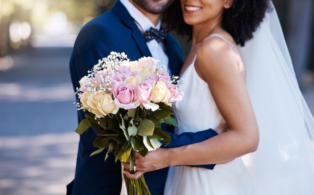 Flowers wedding and marriage with a bride and groom posing outdoor for a photograph at their celebration event or ceremony Rose bouquet love and romance with a newlywed black couple outside