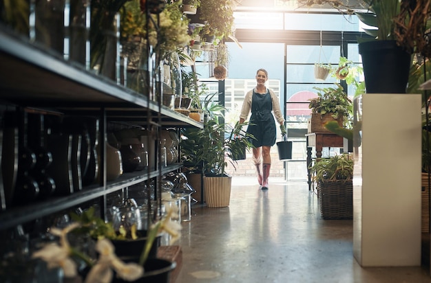 Flowers young florist carrying plants in buckets and in plant nursery with lens flare Agriculture or carbon footprint eco friendly environment and female worker in small business in flower retail