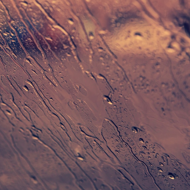 Flowing down drops of rain on car window. Fall concept.