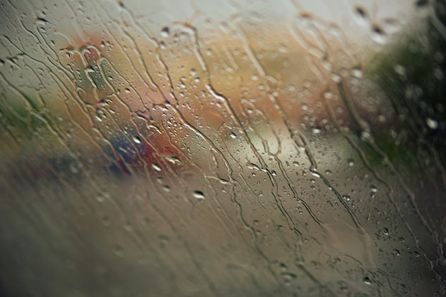 Flowing down raindrops on car window. Fall concept.