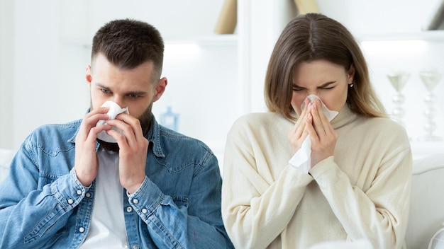 Flu Concept Couple Blowing Noses In Tissues At Home