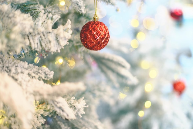 Fluffy artificial snowy frosted christmas tree decorated with red bright balls and fayry lights. Christmas vintage ornaments