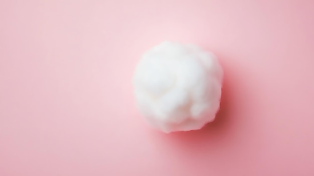 A fluffy white cotton ball on a pink background