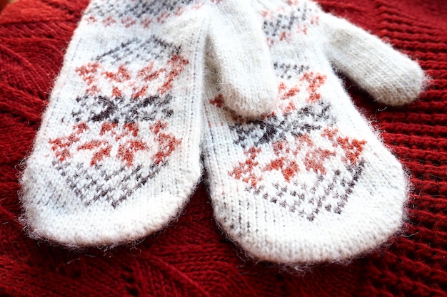 Fluffy white knitted mohair mittens with a traditional floral pattern on the back A pair of mittens fashion accessories Knitted with red and black threads geometric jacquard pattern Winter clothes