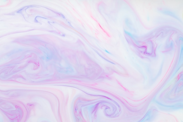 Fluid art multicolored background. Trendy pink backdrop with abstract stains on the liquid. Mixing paints on a liquid surface