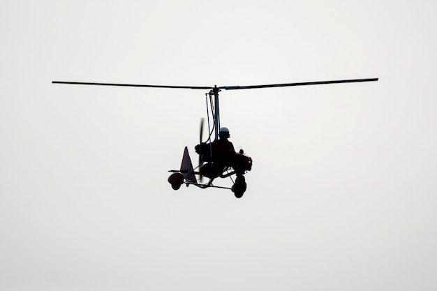 Flying autogyro silhouette on white background.