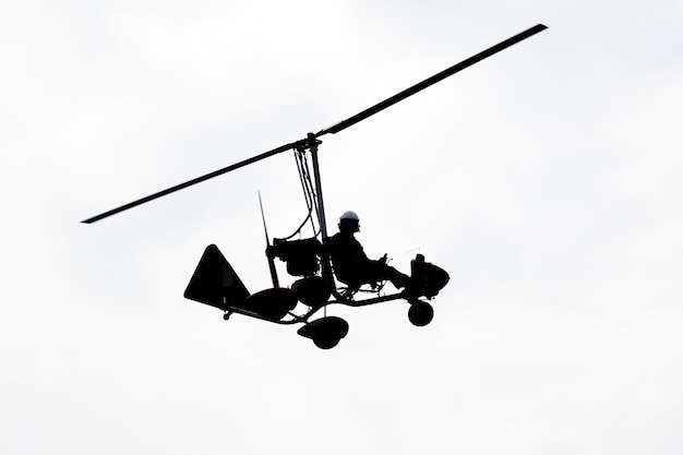 Flying autogyro silhouette on white background.