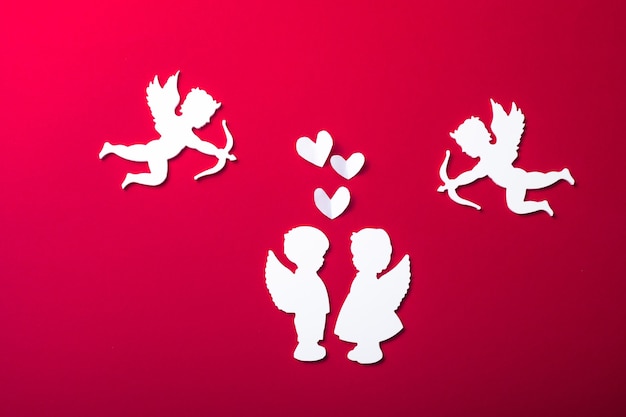 Photo flying cupid silhouette, two white angel,  happy valentine's day banners, paper art style. amour on red paper