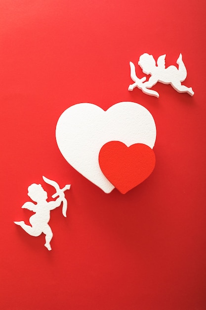 Photo flying cupid silhouette with hearts, gifts, happy valentine's day banners, paper art style. amour on red paper