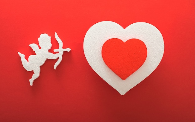 Photo flying cupid silhouette with hearts, gifts, happy valentine's day banners, paper art style. amour on red paper