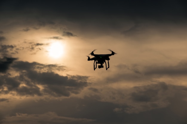 Flying drone with camera on the sky at sunset