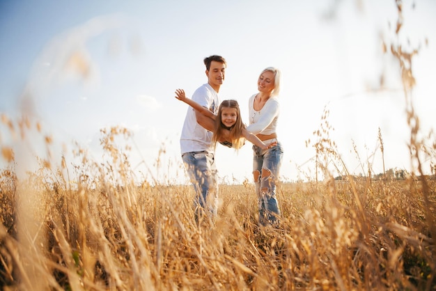 Flying girl in the arms of parents in nature