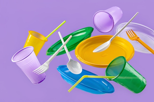 Flying multi-colored plastic utensils on a black background. Environmental protection, recycling pro