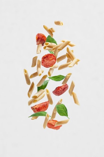 Flying pasta with tomatoes and basil on a gray background