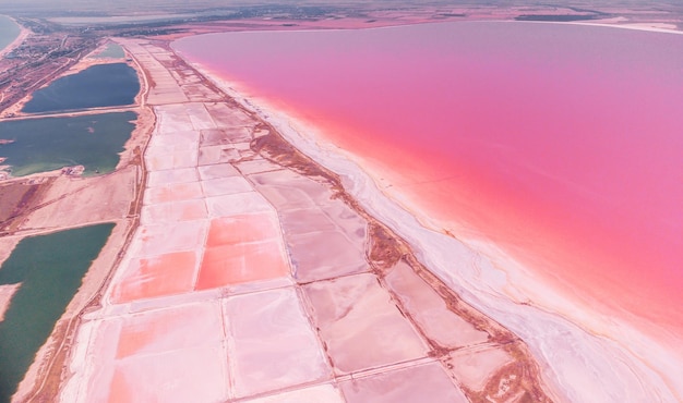 Flying over a pink salt lake Salt production facilities saline evaporation pond fields in the salty lake Dunaliella salina impart a red pink water in mineral lake with dry cristallized salty coast