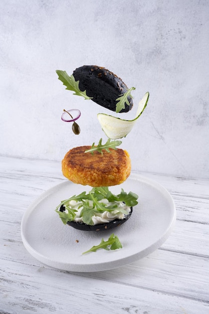 Flying vegan burger with black bun on white background