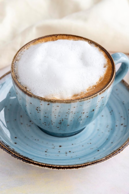 Foam cappuccino on a white wooden background