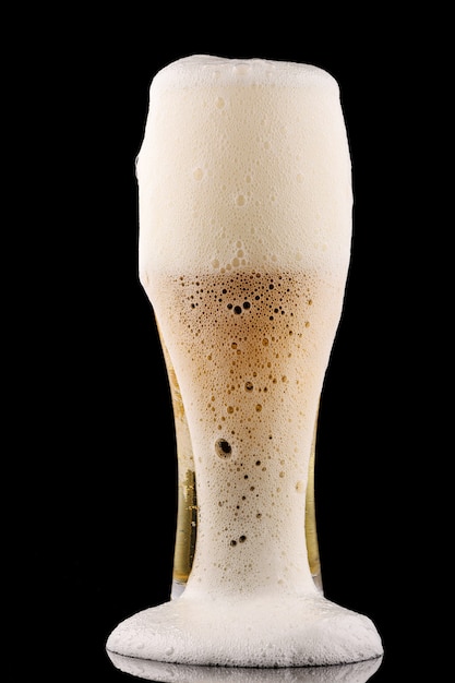 Foam pours from a glass of beer