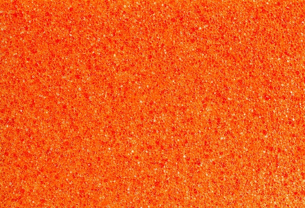 Foam rubber orange sponge pores closeup background wallpaper uniform texture pattern