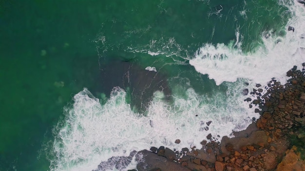 Photo foamy ocean waves splashing on coastal stones aerial view turquoise water