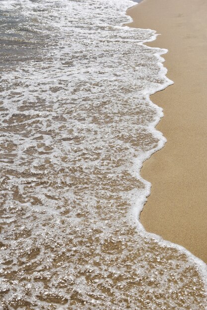 Foamy sea waves on a sandy beach. Shot from above