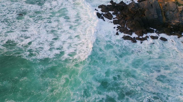 Foamy waves barrelling rocks closeup splashing surf water covering black cliffs