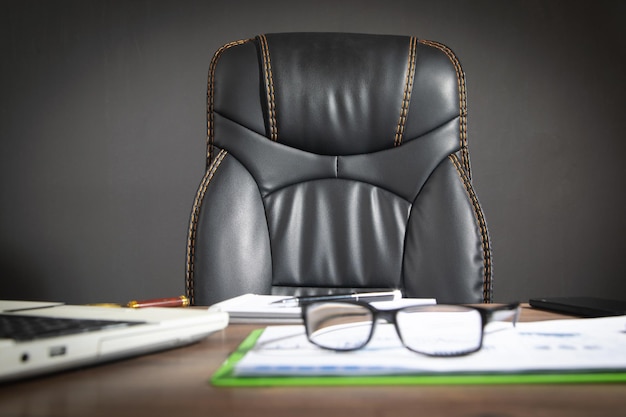 Focus on black leather chair with a office workplace