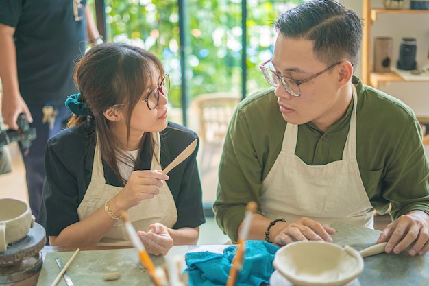 Focus couple potter working on potters wheel making ceramic pot from clay in pottery workshop Couple in love working together in potter studio workshop