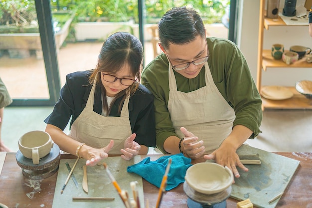 Focus couple potter working on potters wheel making ceramic pot from clay in pottery workshop Couple in love working together in potter studio workshop