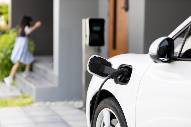 Focus EV car recharging at home charging station for with blur girl in backdrop