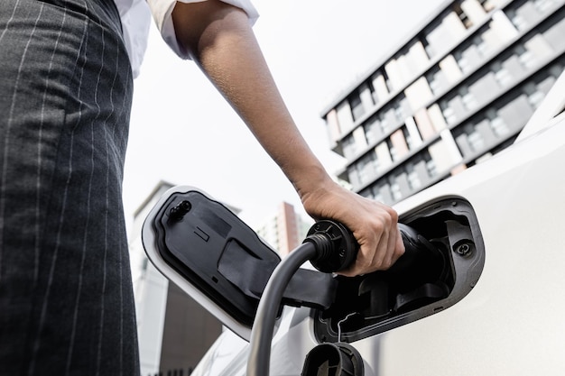 Focus EV charger plug with blur progressive woman charge EV car in background