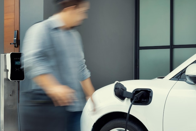 Focus EV charging station at home with blur progressive man in background