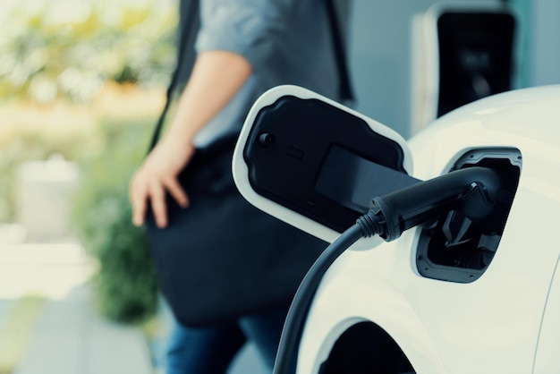 Focus EV charging station at home with blur progressive man in background