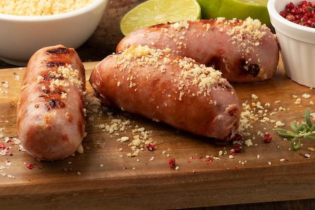 Focus on grilled sausage with toasted manioc flour on cutting board