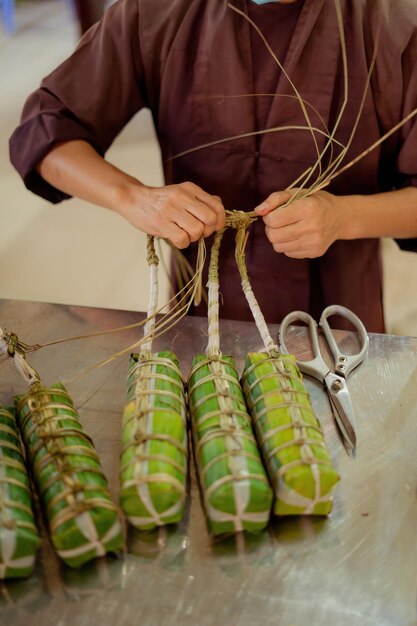 Focus old woman with traditional Vietnamese dress ao ba ba Making wrapping Tet Cake the Vietnamese lunar new year Tet food outdoor by hands