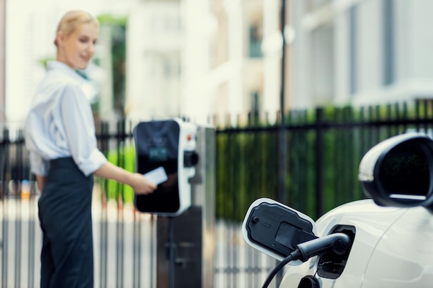 Focus progressive EV recharge with blurred woman using credit card in background