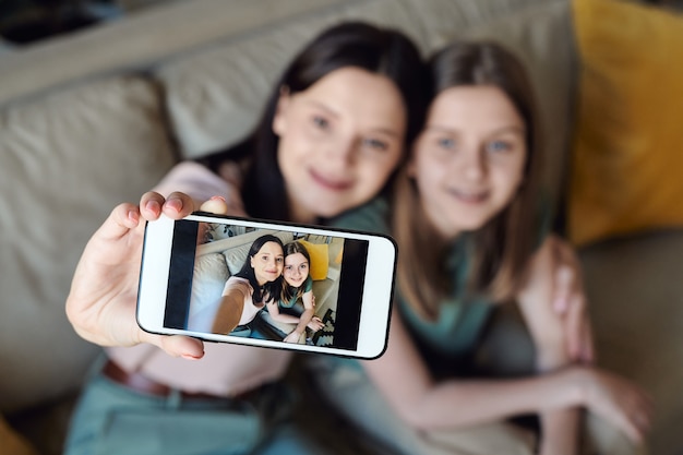 Focus on smartphone screen with selfie of mother and daughter, close relationship between mother and daughter concept